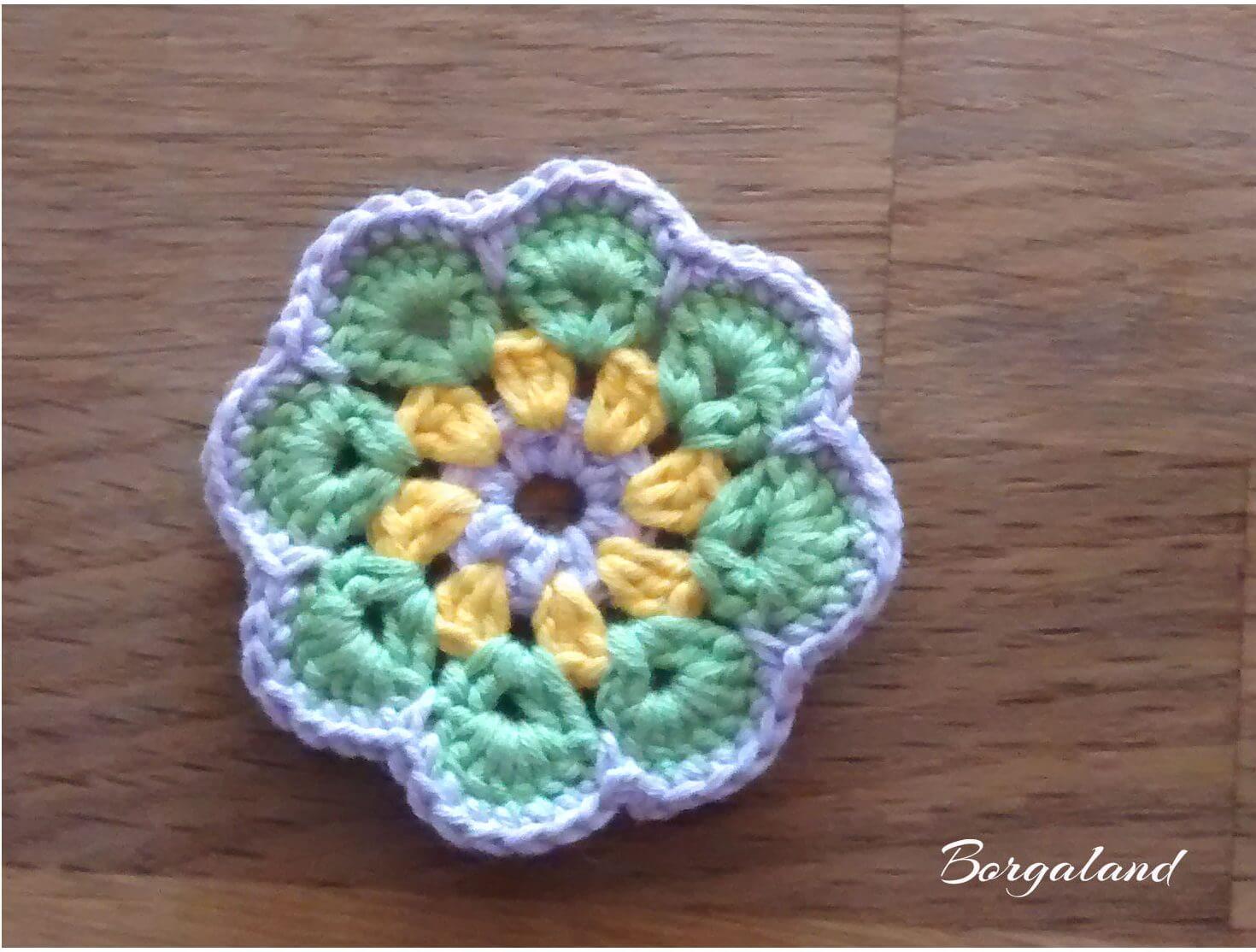 African Flower Blume – gehäkelt vor dem Einrahmen Gehäkelte African Flower Blume mit gelber Mitte und bunten Blütenblättern – noch ohne Umrandung