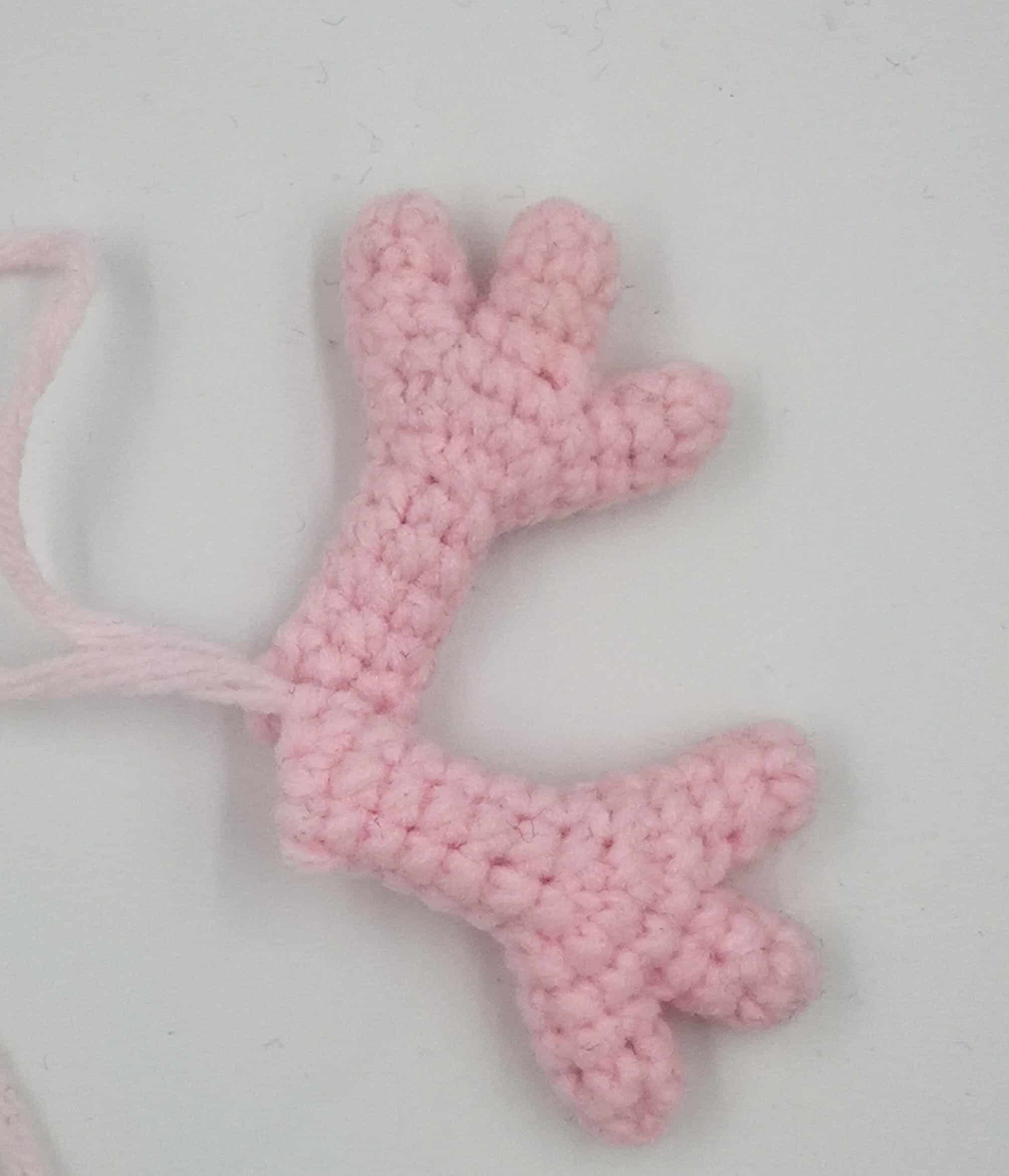 Zwei gehäkelte Arme von Peppa Wutz aus rosa Baumwollgarn, bereit zum Zusammennähen