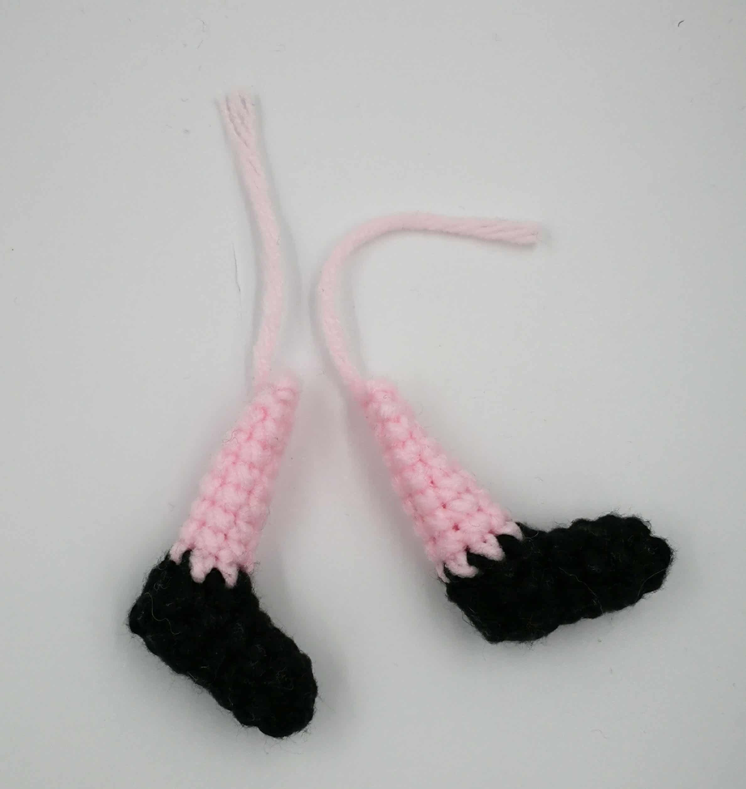 Zwei gehäkelte Beine mit schwarzen Schuhen und rosa Beinen – vorbereitete Teile für die Peppa-Wutz-Figur