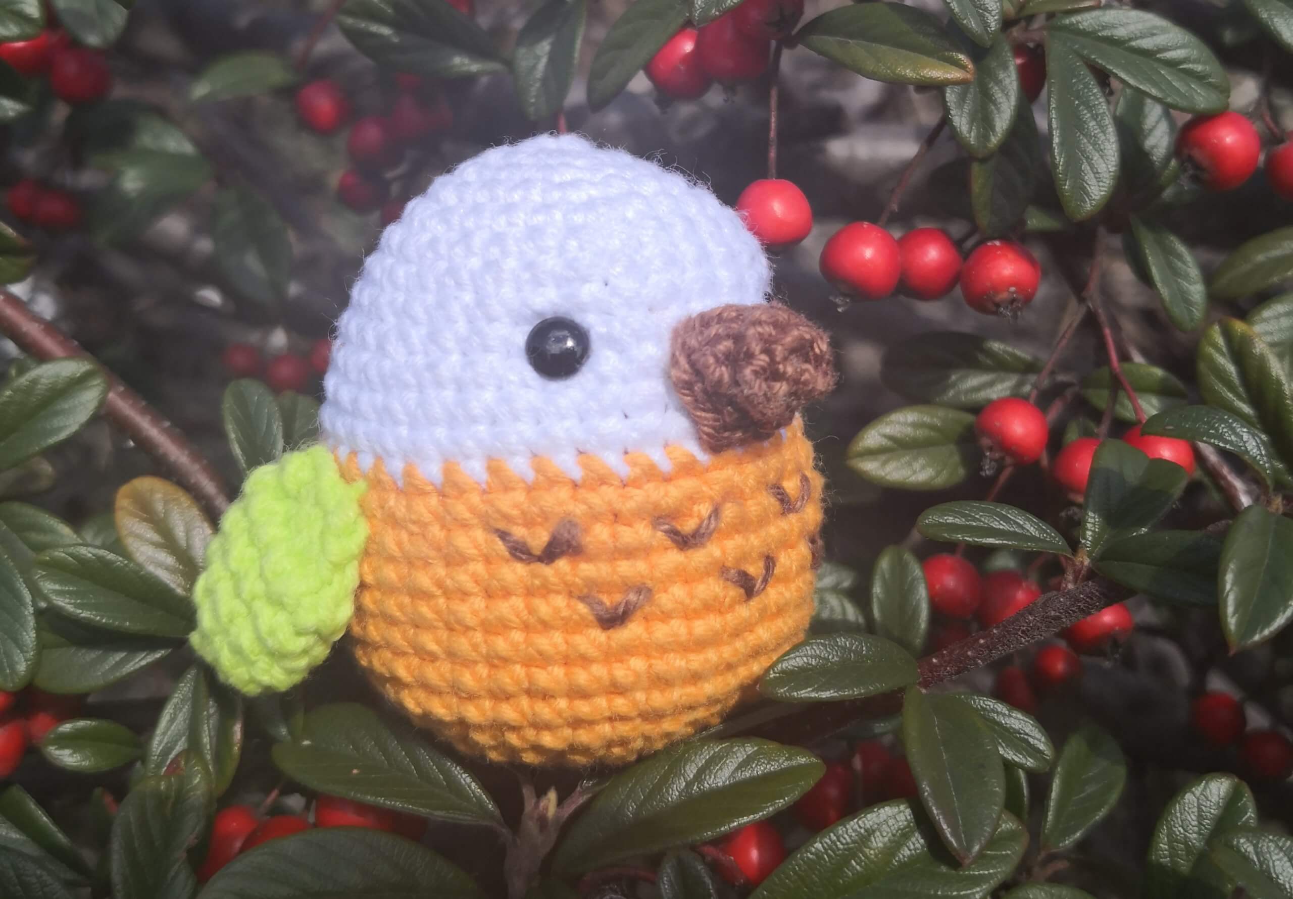 Gehäkelter Vogel mit gelben Flügeln im Strauch – Amigurumi Dekoidee