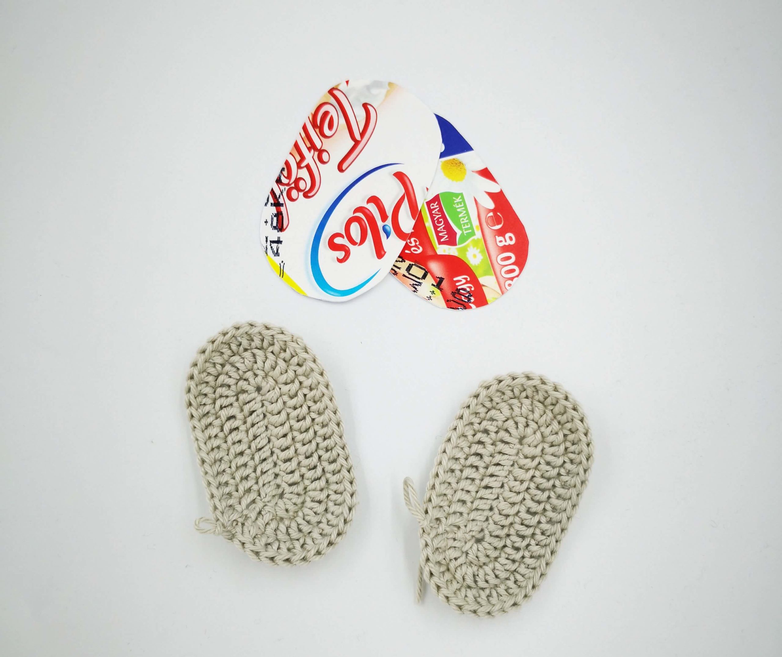 Zwei ausgeschnittene Sohlen aus Joghurtdeckel für gehäkelte Amigurumi-Schuhe – einfache, waschbare Verstärkung