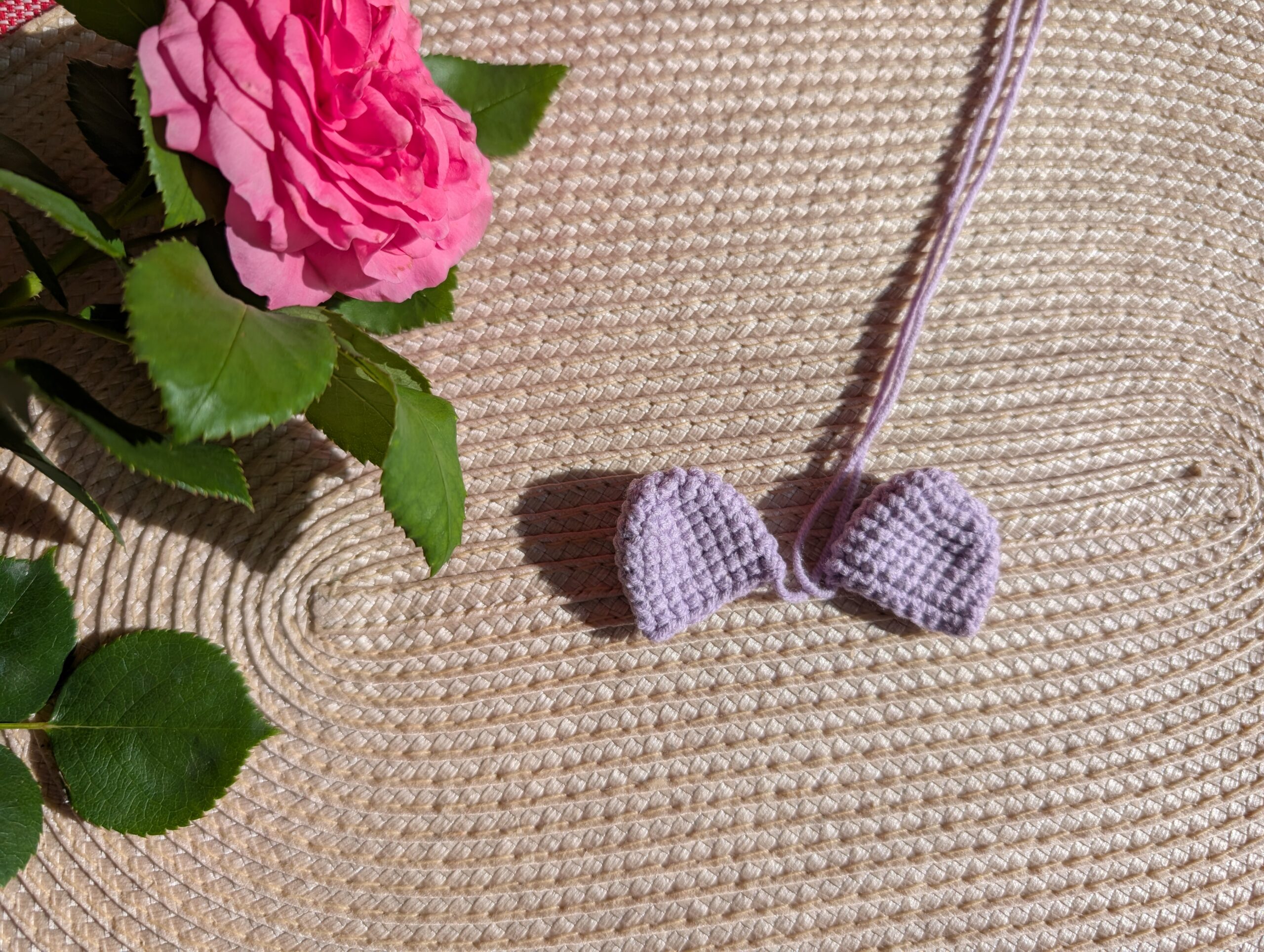 Gehäkelte Ohren einer Amigurumi-Giraffe – lila Farbtöne, auf Jutestoff präsentiert.