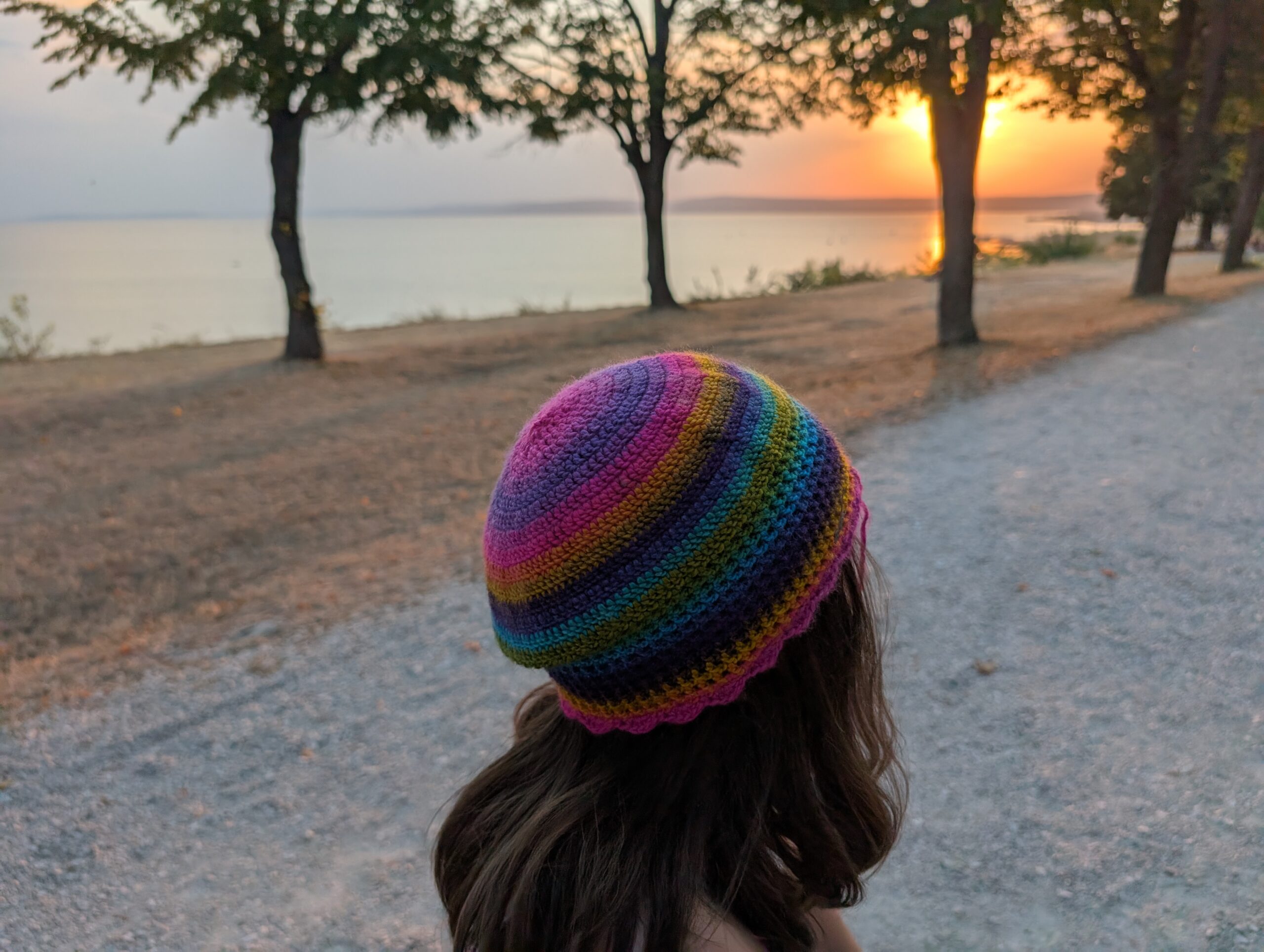 Mädchen trägt Borgaland Regenbogen-Mütze – Anleitung für Mütze häkeln im Sonnenuntergang