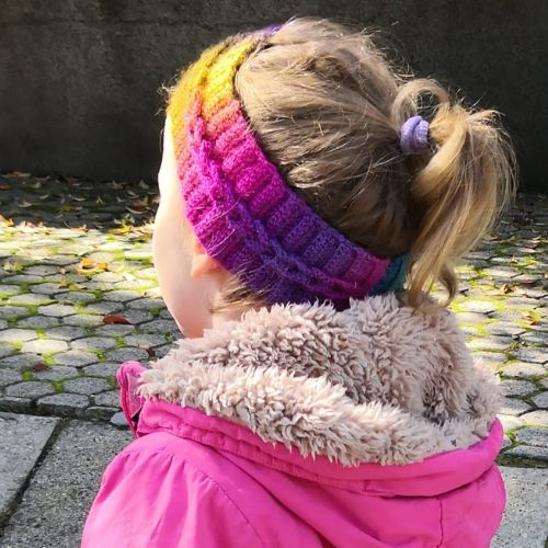 Stirnband häkeln: Kind mit Regenbogen-Stirnband im Schlaufenmuster, elastische Rippe.